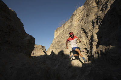 One man trail running on a small canyon with high contrast light