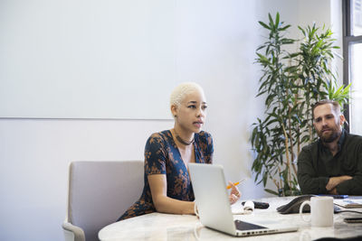 Businesswoman explaining while sitting with colleague in conference room