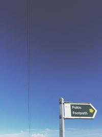 Low angle view of road sign against clear blue sky