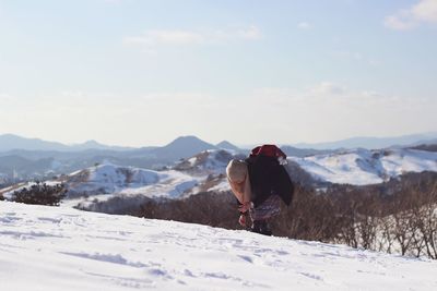 Woman on snowcapped mountain peak against sky