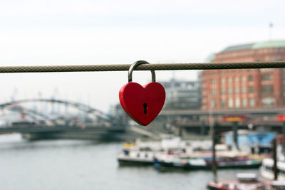 Close-up of love lock on railing with city in background