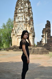 Portrait of young woman standing against old ruin temples