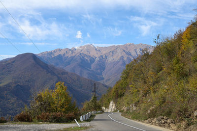 Road by mountains against sky