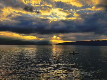 Scenic view of sea against cloudy sky during sunset