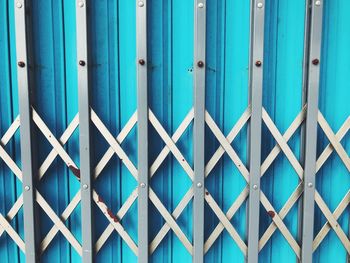 Full frame shot of metallic fence against blue wall