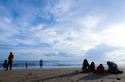 People at beach against sky