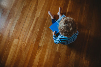 High angle view of boy sitting on wooden floor