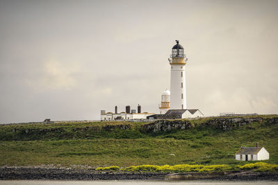 Lighthouse on field against sky