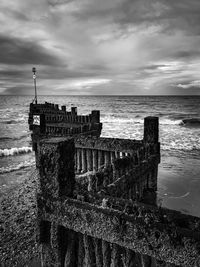 Built structure on beach against cloudy sky