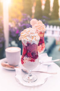 Strawberry ice cream dessert with whipped cream and crushed meringue, served in a glass cup. 