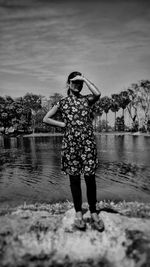 Full length of woman standing by lake against sky