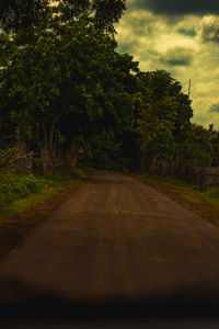 Empty road amidst trees against sky