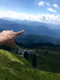 Personal perspective of person pointing at mountainous landscape