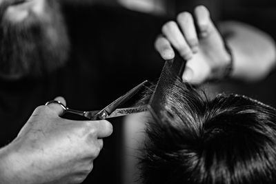 Cropped image of barber cutting man hair in shop