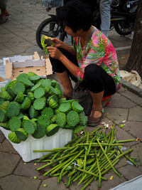 Full length of woman holding vegetables for sale at market stall