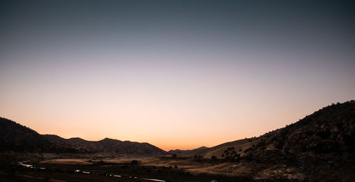 Scenic view of silhouette mountains against clear sky during sunset