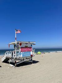 Scenic view of beach and lifeguard hut against clear blue sky