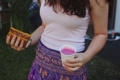 Midsection of woman holding drink while standing outdoors