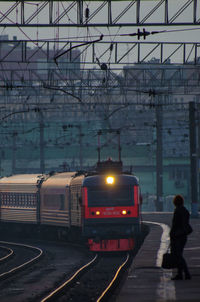 Person standing on platform by train in city