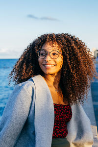 Portrait of a smiling young woman against sky