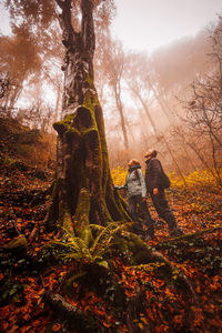 People standing by trees in forest during autumn