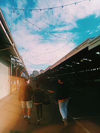 Rear view of people walking on bridge against sky