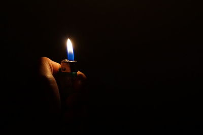 Close-up of hand holding cigarette lighter on black background