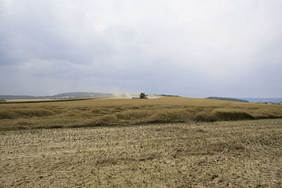 View of agricultural fields against cloudy sky