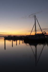 Silhouette sailboats in lake against sky during sunset