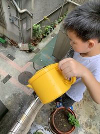 High angle view of cute boy pouring water while standing in balcony