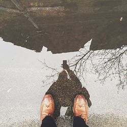 Reflection of person photographing on puddle