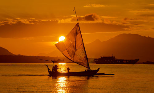 Silhouette sailboat on sea against sky during sunset