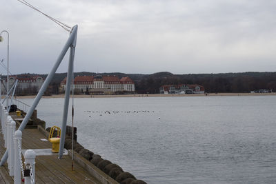Sailboats in sea by buildings against sky