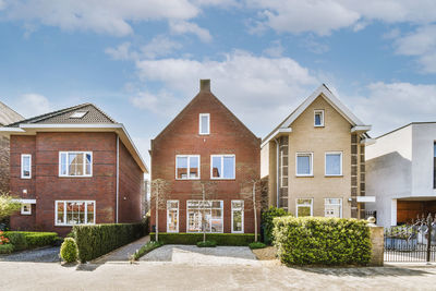 The front view of a brick building with signs, pavement and wooden doors lead to the apartment