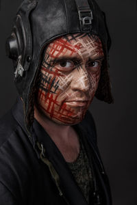 Close-up of man with face paint against black background