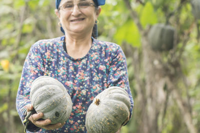 Portrait of smiling woman standing against plants