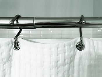 Close-up of white curtain on metallic rod at bathroom