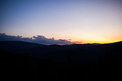 Scenic view of silhouette mountains against clear sky at sunset