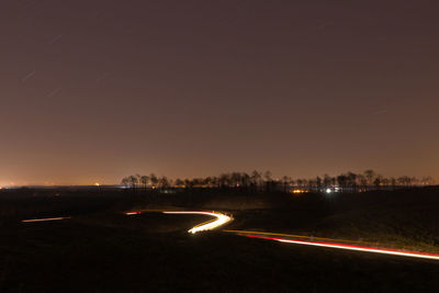 Light trails on road against sky at night