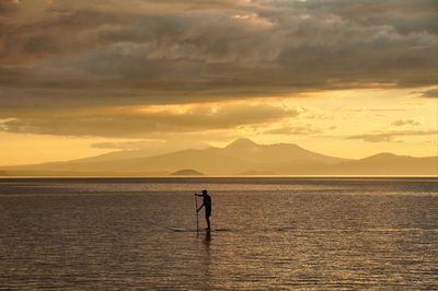 Man doing stand-up paddle on sunset