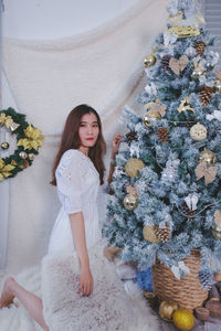 Full length of woman standing by christmas tree