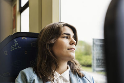 Thoughtful young woman looking through tram window