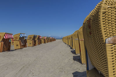 Hooded chairs on beach against clear blue sky