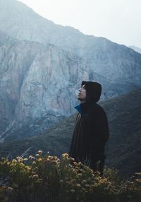 Side view of man wearing hat against mountains