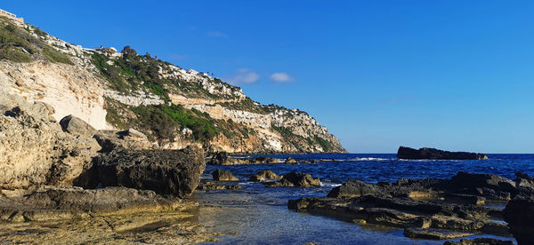 Scenic view of sea and mountains against blue sky