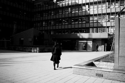 Rear view of woman walking on building in city