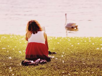 Rear view of woman looking away while sitting on grass