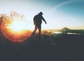 The man climber in inspirational sunrise landscape on mountain peak.