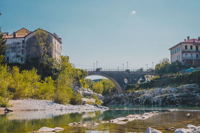 Bridge over river by buildings against sky