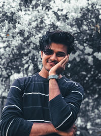 Portrait of young man standing against trees